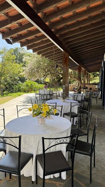 Varanda com mesas postas com toalhas brancas e flores