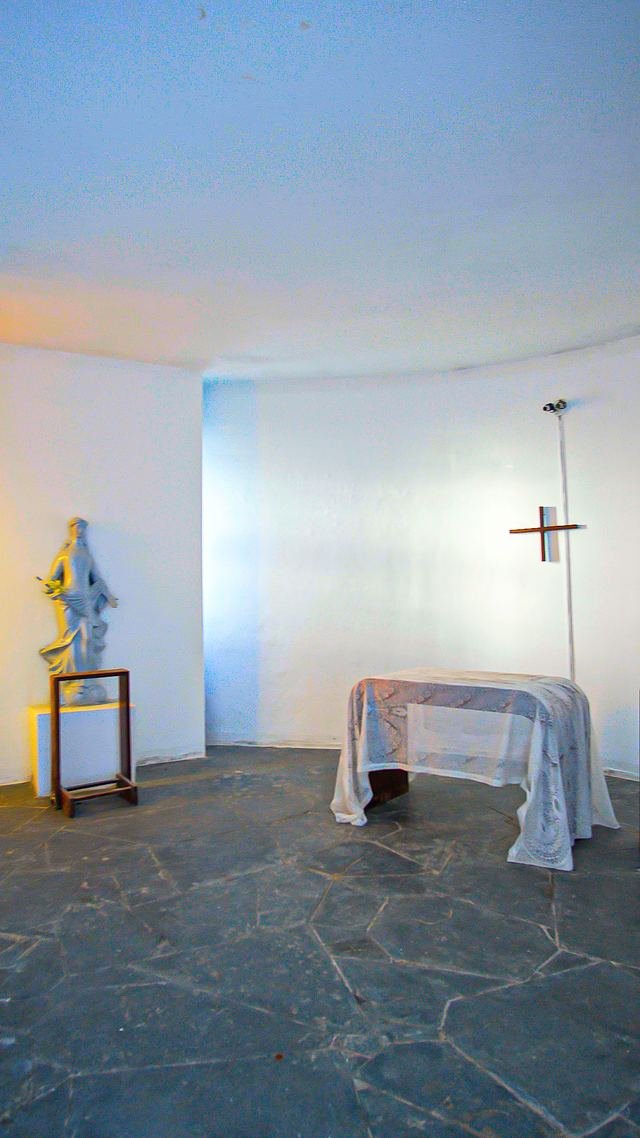 Interior branco da capela com imagem sacra